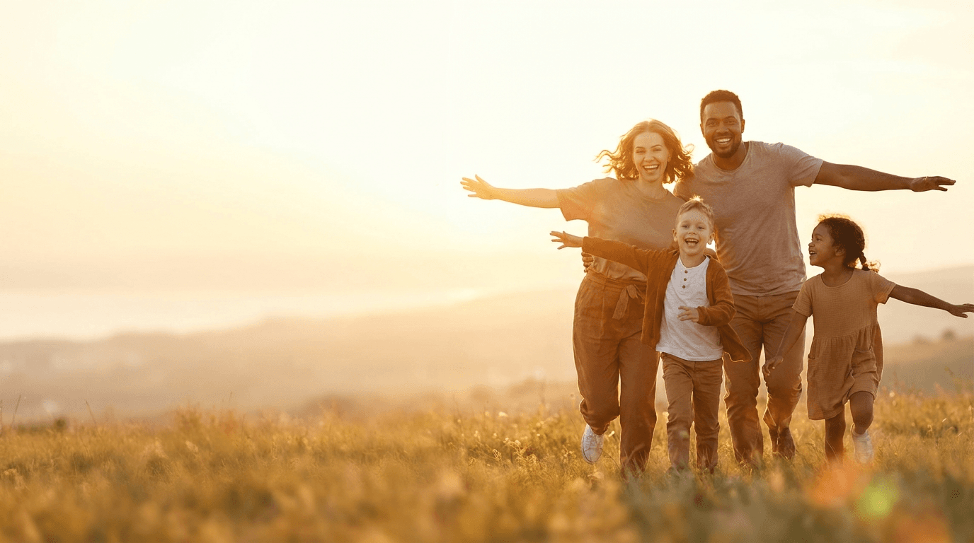 A family laughing together in an open field at sunset